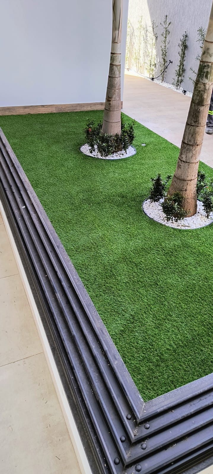 Grama sintética em jardim interno com pedras brancas