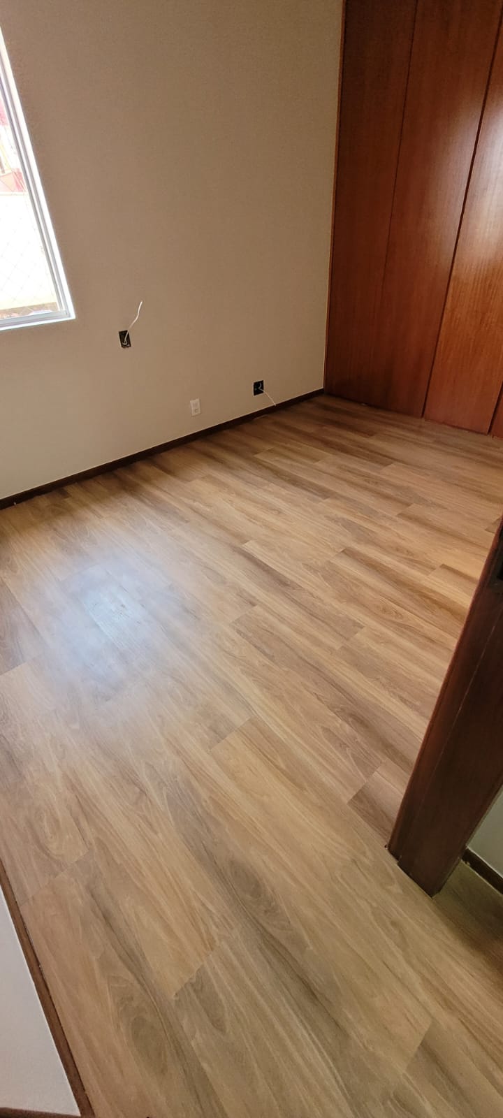 Piso laminado em corredor de acesso com janelas altas
