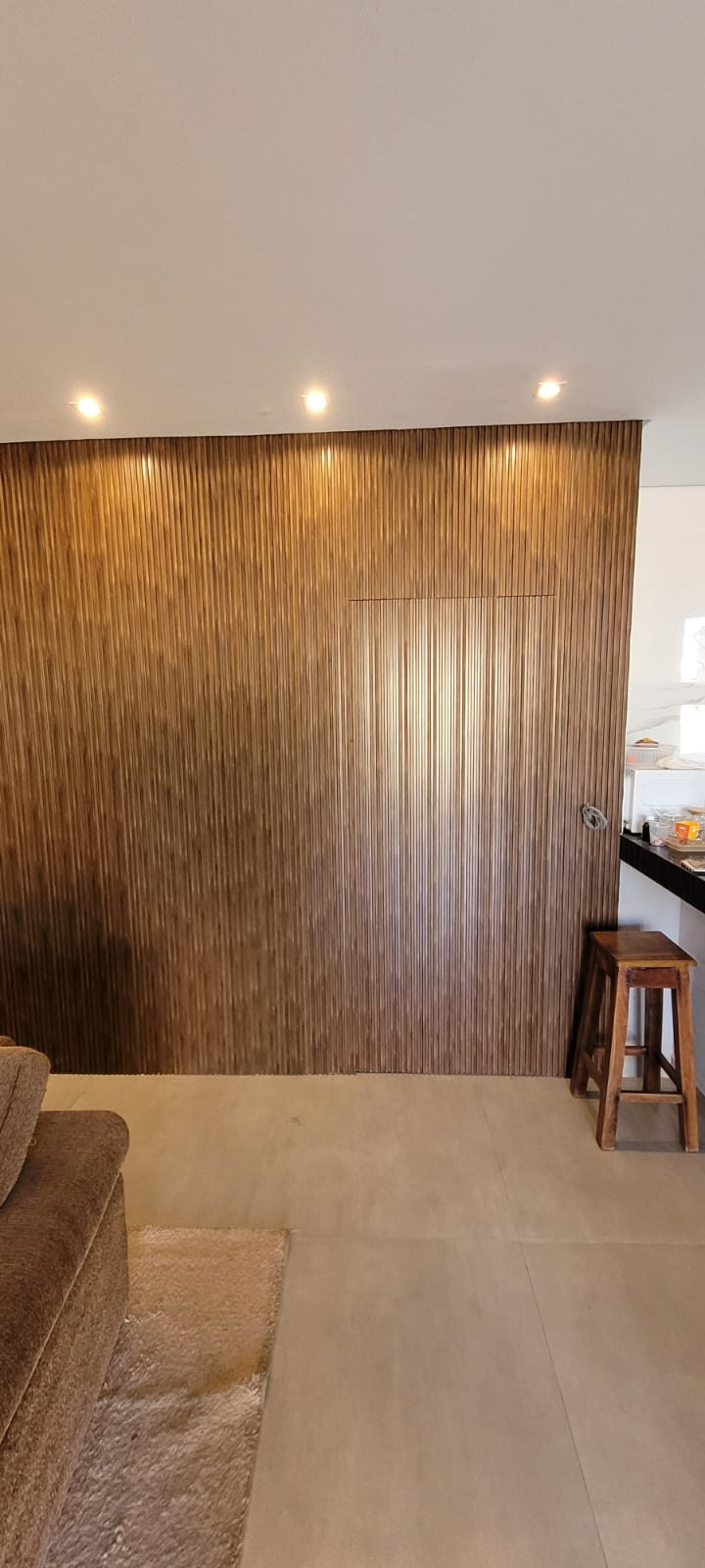 Parede interna revestida com ripado de madeira em sala de estar